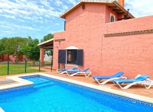 - une piscine avec 2 chaises longues et une maison dans l'établissement Agradable casa de playa con piscina. El Palmar, à El Palmar