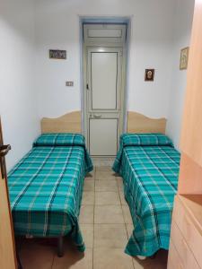 two beds sitting in a room with a door at La Casa di Nino in Catania