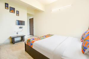 a white bedroom with a bed and a television at Via Shivsai Palace - Nr Shree Krishna Temple in Kharadi