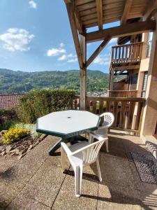 a picnic table and two white chairs on a patio at Hameau des chaumes vue panoramique in La Bresse
