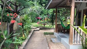 einen Garten mit Blumen und eine Veranda mit einer Hängematte in der Unterkunft Bale Kebon Rangsot in Pawenang