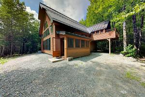 a wooden cabin with a driveway in the woods at The Lazy Lumberjack Cottages in Franklin