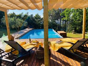 a deck with a table and chairs next to a swimming pool at Casa di Coraggio in Volterra