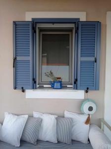 uma janela com persianas azuis e um sofá com almofadas em Seaside resort- kallithea 