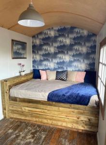 a bedroom with a bed with a blue wall at Moon Valley Glamping 