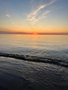 a sunset over a body of water with a beach at Międzywodzie Park Dom na wyłączność ok 250 m od plaży in Międzywodzie