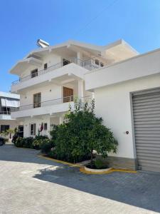 a white building with a parking lot in front of it at Guest House Lionel in Durrës