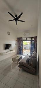 a living room with a couch and a ceiling fan at 4 bedroom homestay @ Mersing in Mersing