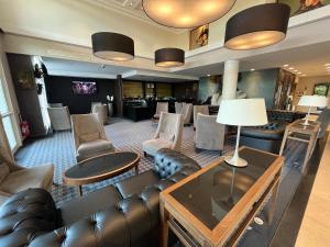 a living room with leather furniture and a waiting room at City Résidence Paris CDG Airport in Roissy-en-France