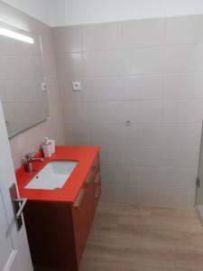 Un baño con un lavabo rojo y un espejo. en Apartamento laranja, en Quarteira