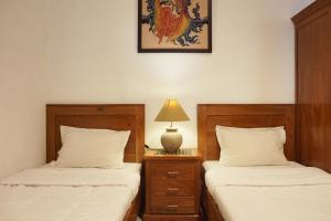 a bedroom with two beds and a lamp on a night stand at RedDoorz at Griya Cemara Homestay Yogyakarta in Yogyakarta