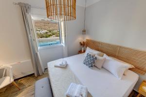 1 dormitorio con 1 cama blanca grande y ventana en Villa Mare Syros, en Finikas