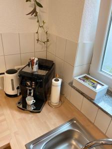 a kitchen counter with a coffee maker and a sink at Ferienwohnung im Sand in Herbolzheim