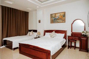 a bedroom with two beds and a dresser and a mirror at Thao Vy Hotel in Hai Phong