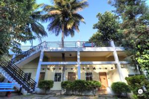 uma casa com uma palmeira na varanda em Coorg Avani Holiday Inn em Madikeri