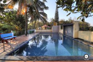 een zwembad met een blauwe bank naast een huis bij Coorg Avani Holiday Inn in Madikeri