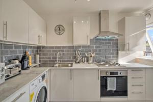 a white kitchen with a sink and a dishwasher at Hidden Gem in Battersea w/ Free Parking in London