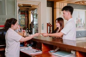 um homem e uma mulher apertando as mãos num balcão em Thao Vy Hotel em Haiphong