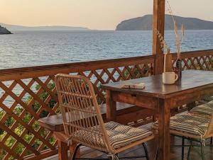 una mesa de madera y sillas en una terraza con vistas al agua en Santa Maria - Seaside Serenity en Ierápetra