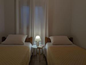 イエラペトラにあるSanta Maria - Seaside Serenityのベッド2台、ランプ1台、テーブルが備わる客室です。