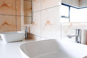 a bathroom with a white tub and a sink at L. A. P Guesthouse in Windhoek