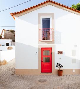 a red door on a white house at A Casa do Maltês in Belver