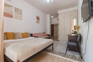 a bedroom with a bed and a couch and a television at Апартаменты в ЖК Expo Residence C in Taldykolʼ