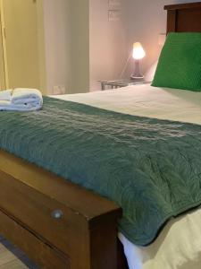 a bed with a green comforter on top of it at The Nash Suite - one minute walk to beach in Brighton & Hove