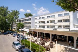a large white building with cars parked in a parking lot at Hotel Venus in Mamaia
