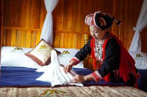Eine Frau macht ein Kleid auf einem Bett in der Unterkunft Hoàng Su Phì - Móng Ngựa Homestay in Ha Giang
