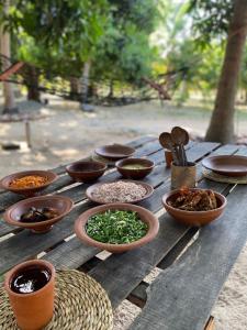 a wooden table with bowls of food on it at Kirãmam Villa in Pasikuda