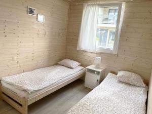 dwa łóżka w pokoju z oknem w obiekcie Domki Laba w Łebie