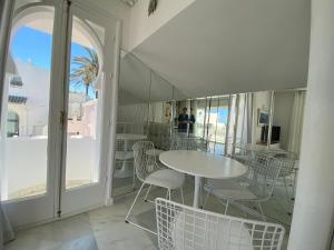 una mesa y sillas blancas en una habitación con ventana en GOLDEN MILE FRONT LINE BEACH RESORT en Marbella