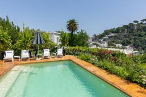 a swimming pool with chairs and an umbrella on a house at Villa La Pergola Capri in Capri
