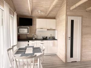 uma cozinha com armários brancos e uma mesa e cadeiras em Domki Laba em Łeba