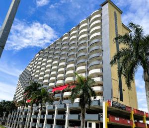 un edificio alto con palmeras delante en Dindings Pantai Desair Apartment By DPD en Lumut