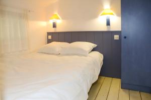 een slaapkamer met een groot wit bed met 2 verlichting bij Olydea Oleron les Sables Vignier in Saint-Georges-dʼOléron
