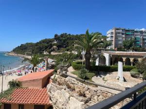 a view of a beach with palm trees and a building at Casa con jardín en Roda de Bará in Roda de Bará