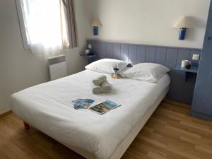a bed with a teddy bear and a book on it at Olydea Oleron les Sables Vignier in Saint-Georges-dʼOléron