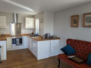 a kitchen with white cabinets and a red couch at 18 Mill Wharf Apartment in Berwick-Upon-Tweed