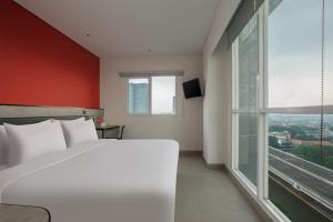 a bedroom with a white bed and a large window at Amaris Hotel Kalimalang in Jakarta