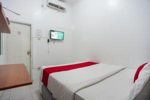 RedDoorz Syariah near PGC Cililitan في جاكرتا: غرفة نوم مع سرير وتلفزيون على الحائط