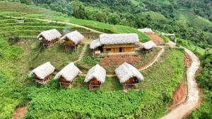 une petite maison sur une colline avec des toits de gazon dans l'établissement Hoàng Su Phì - Móng Ngựa Homestay, à Ha Giang