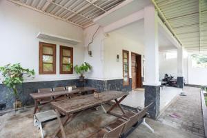 a room with two wooden tables and benches at RedDoorz Syariah near PGC Cililitan in Jakarta