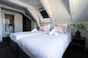 a bedroom with two beds with pink and white pillows at Multatuli Hotel in Amsterdam