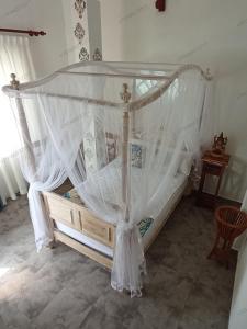 a bed with a canopy in a room at Villa Music of the ocean in Wadduwa