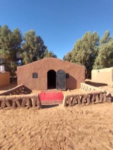 um pequeno edifício no meio de um campo de terra em Visitors camp em M'hamid