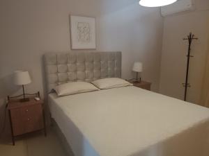 a bedroom with a large white bed with two lamps at Airport Family House in Artemida