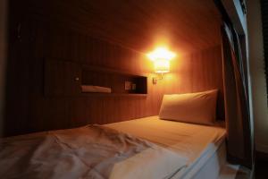 a bedroom with a bed with a light on it at The poshtel Bangkok By Benya in Bangkok