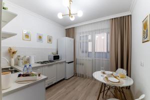 a white kitchen with a table and a white refrigerator at ЖК "Light House", 1 in Astana